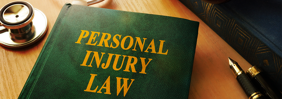 A book titled personal injury law is on a table next to a stethoscope and a pen. A book titled personal injury law is on a table next to a stethoscope and a pen.
