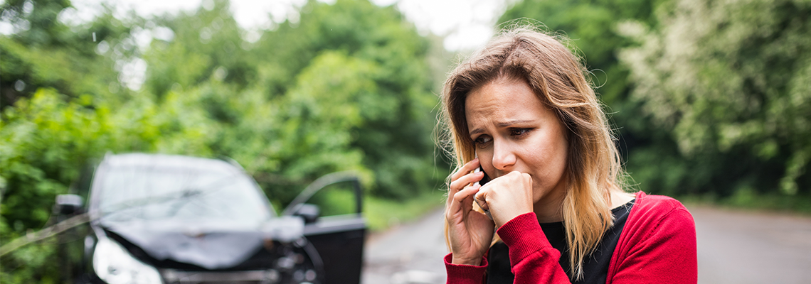 A woman is crying in front of a car that has been involved in a car accident. A woman is crying in front of a car that has been involved in a car accident.