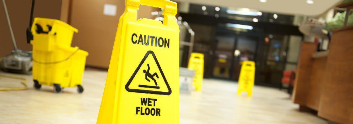 A yellow caution wet floor sign is in a lobby. A yellow caution wet floor sign is in a lobby.