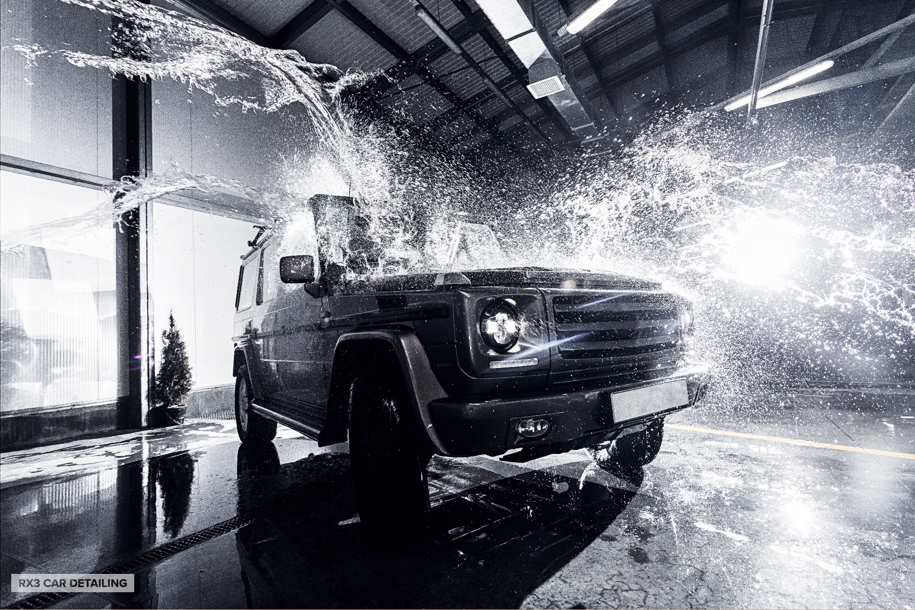 A black and white photo of a car being sprayed with water.