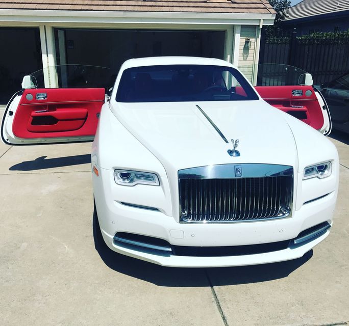 A white rolls royce parked in front of a garage