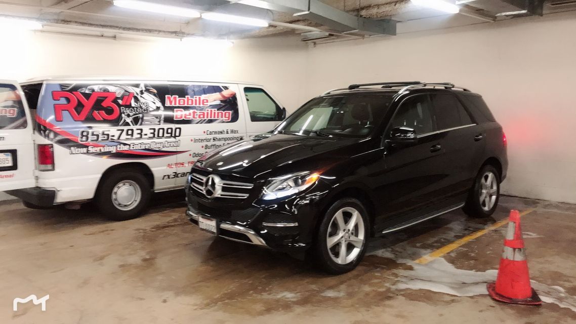 A black suv is parked next to a white van in a parking garage.