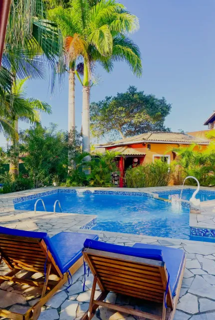 Piscina de resort tropical com água azul, palmeiras e espreguiçadeiras em primeiro plano.