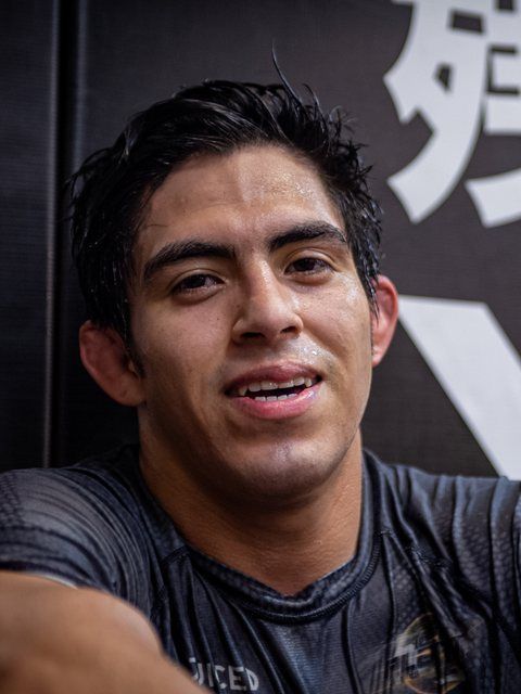 Close-up of a smiling person in a dark shirt against a black-and-white background