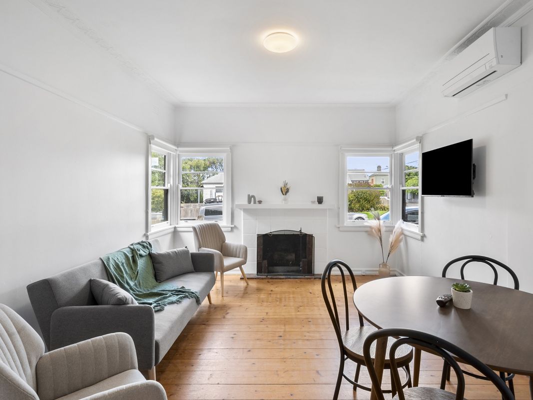 Bright and spacious living room with fireplace, dining area and large windows at York Street Geelong accommodation