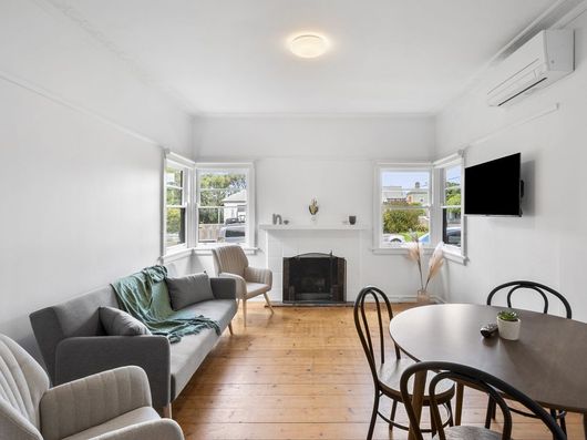 Bright and spacious living room with fireplace, dining area and large windows at York Street Geelong accommodation