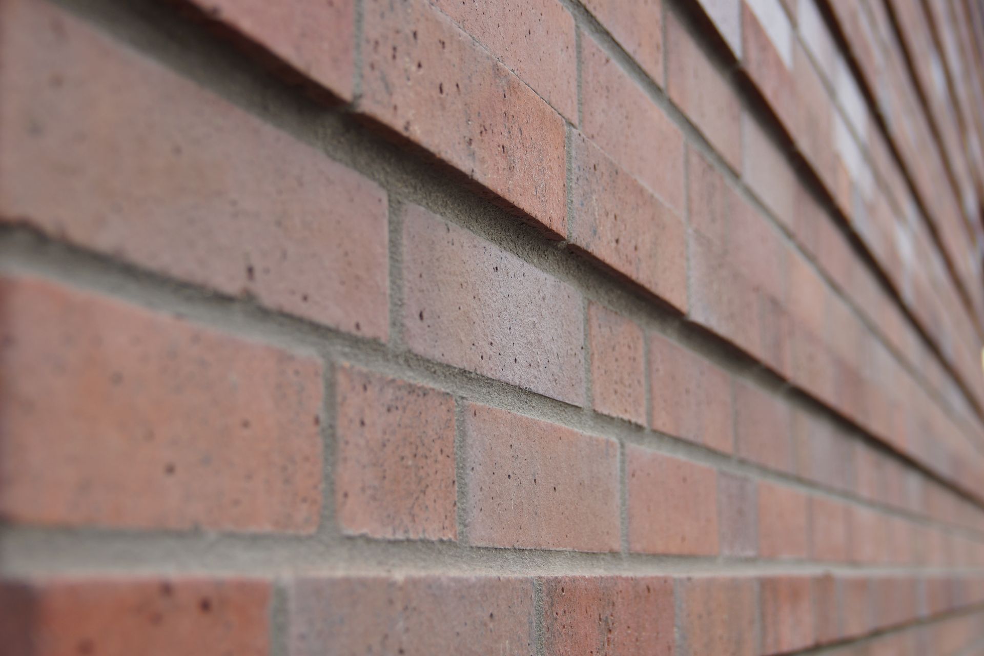 Eine Nahaufnahme einer roten Backsteinmauer mit unscharfem Hintergrund.