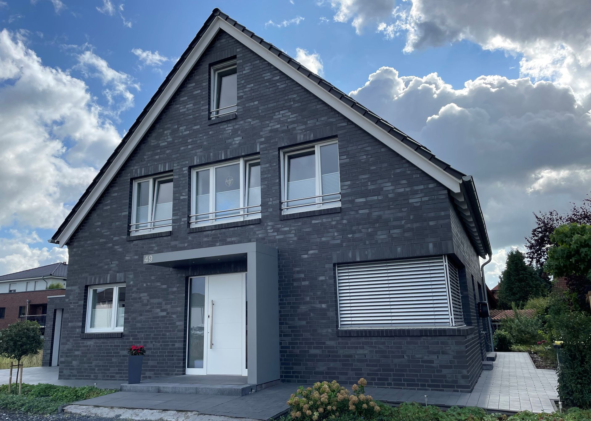 Ein schwarzes Backsteinhaus mit weißen Fenstern und einer weißen Tür