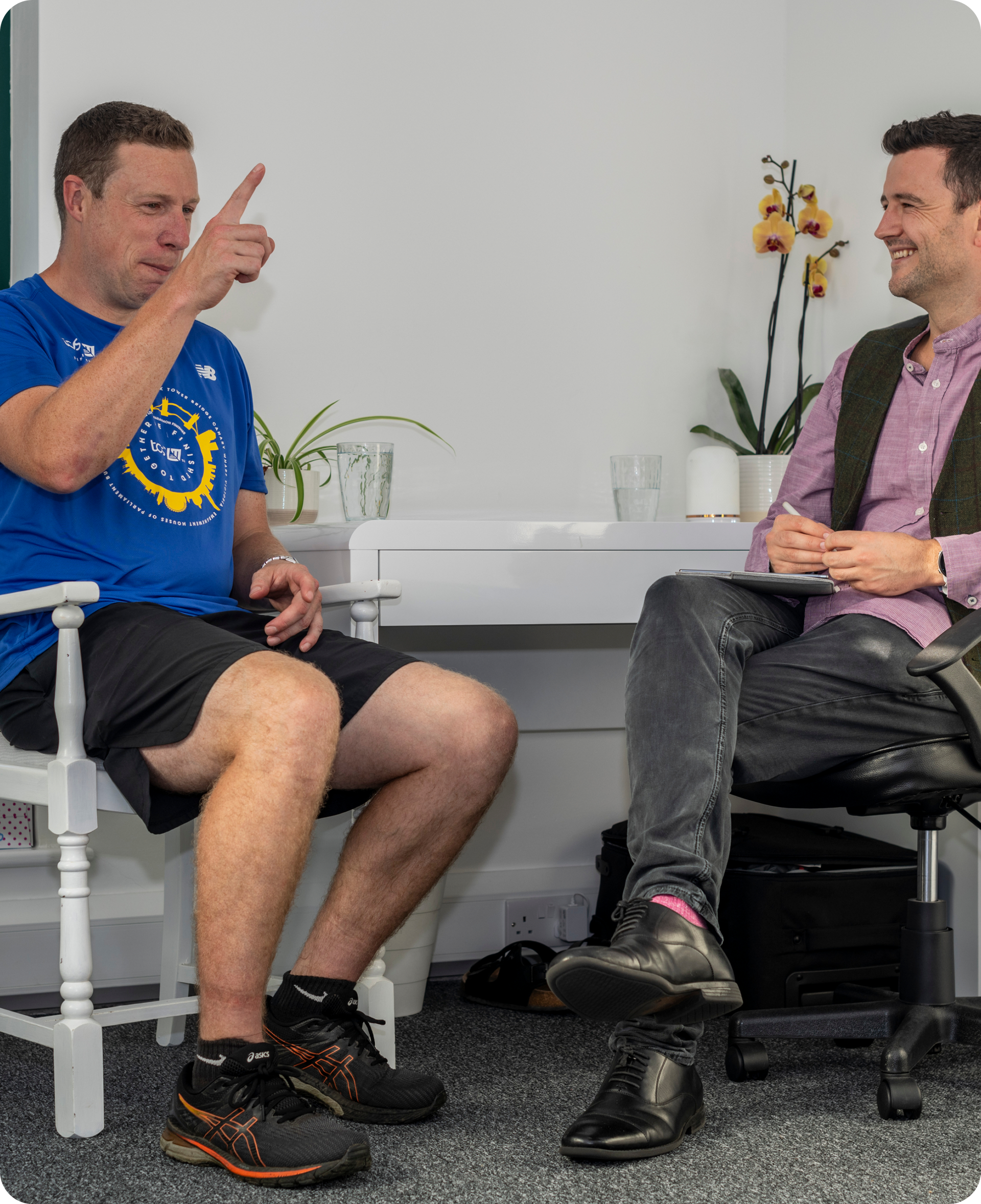 An acupuncture consultation where a male patient is sitting to the left of the acupuncturist whilst explaining his health.