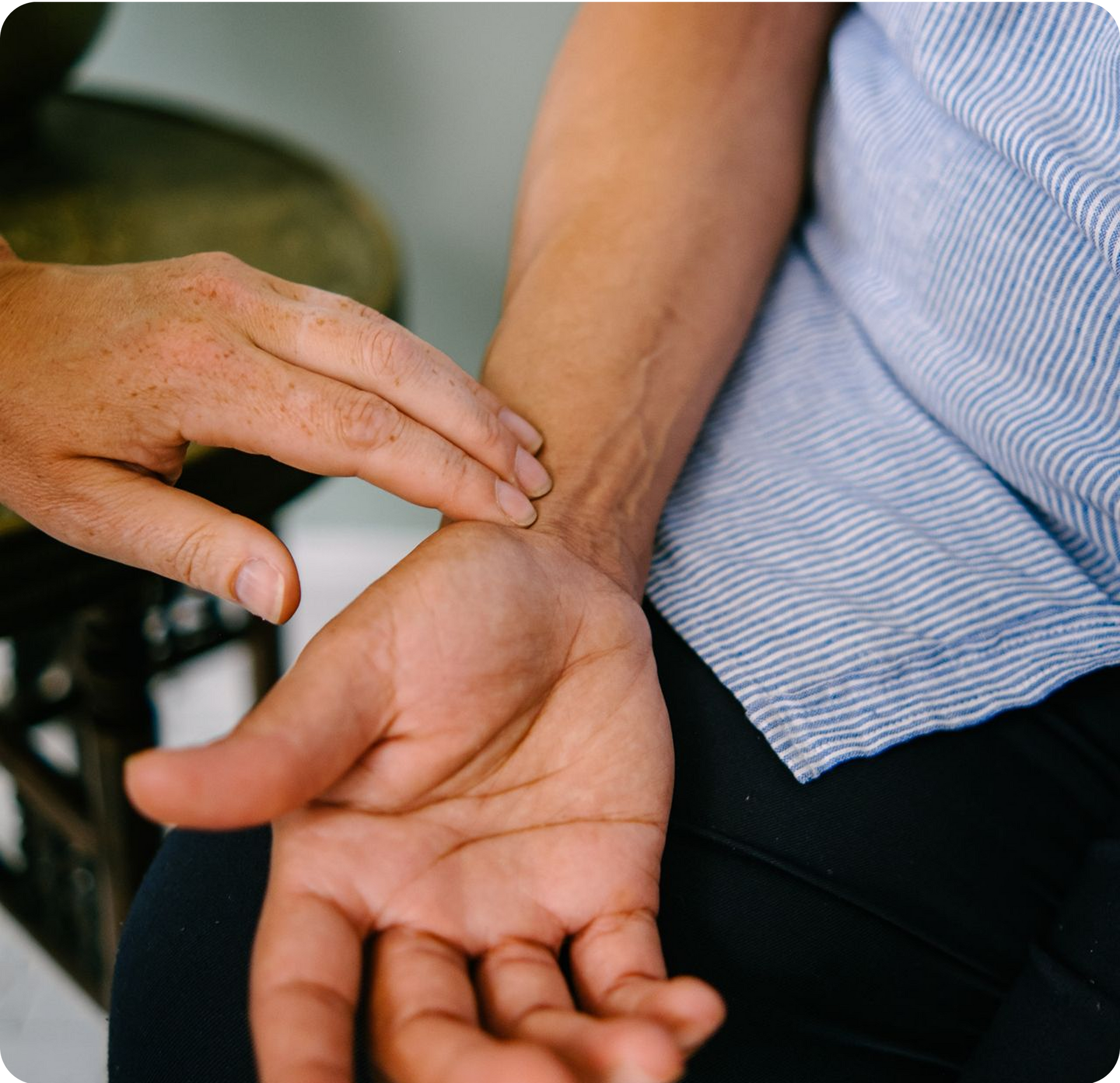 A close-up of an acupuncturist reading a patient's pulse who is lying down. It's a key diagnostic pillars of acupuncture.