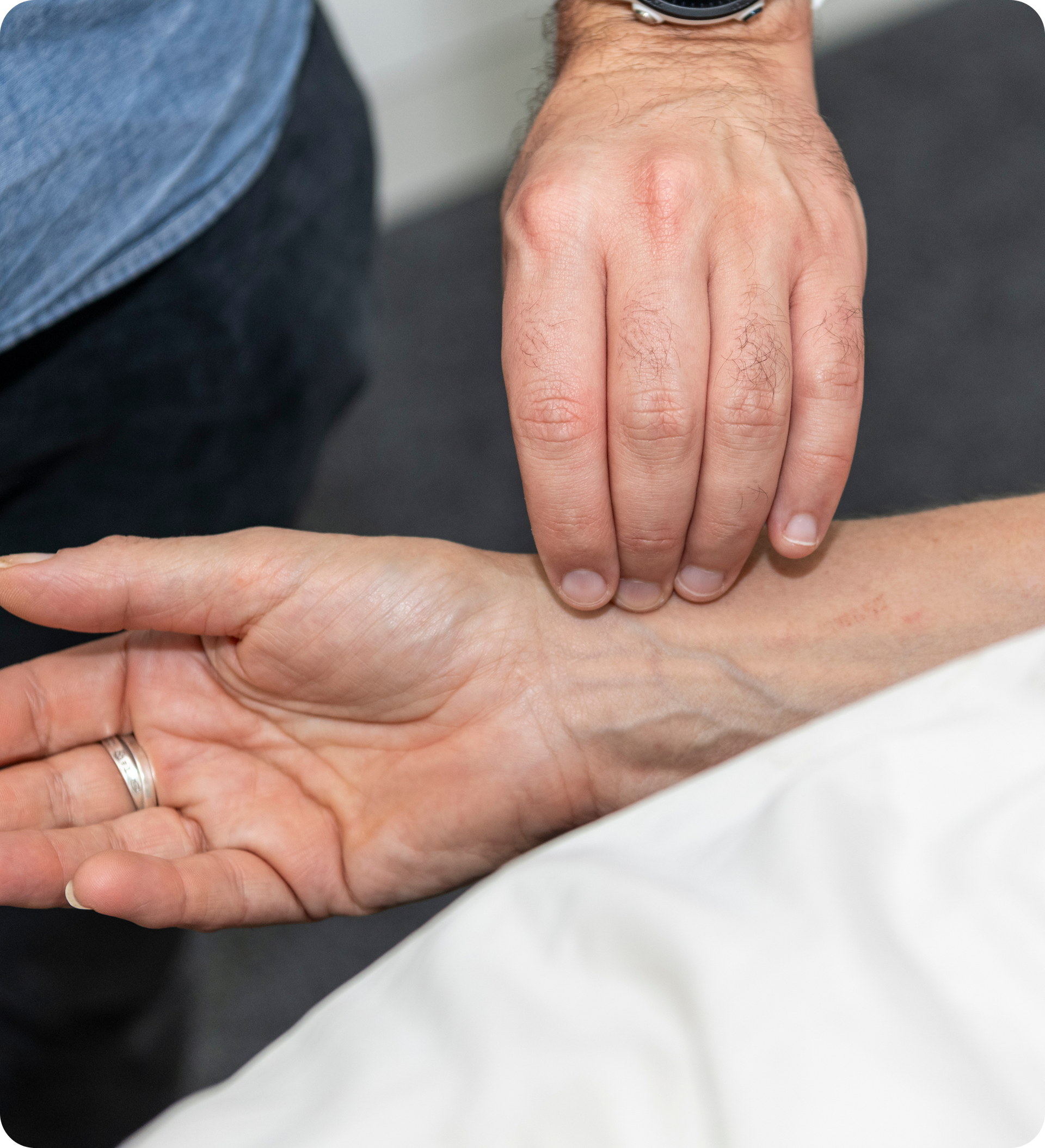 A close-up of an acupuncturist reading a patient's pulse who is lying down. It's a key diagnostic pillars of acupuncture.