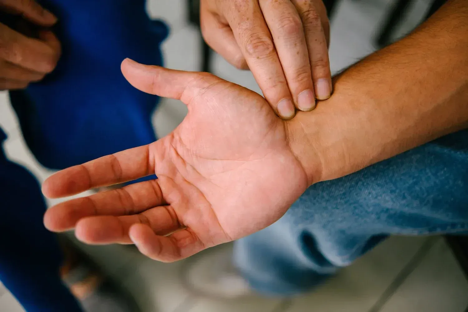 A close-up of an acupuncturist reading a patient's pulse who is lying down. It's a key diagnostic pillars of acupuncture.