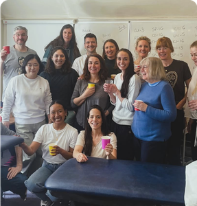 An image of a points class, with around 14 people, stood celebrating completing learning all of the acupuncture points.