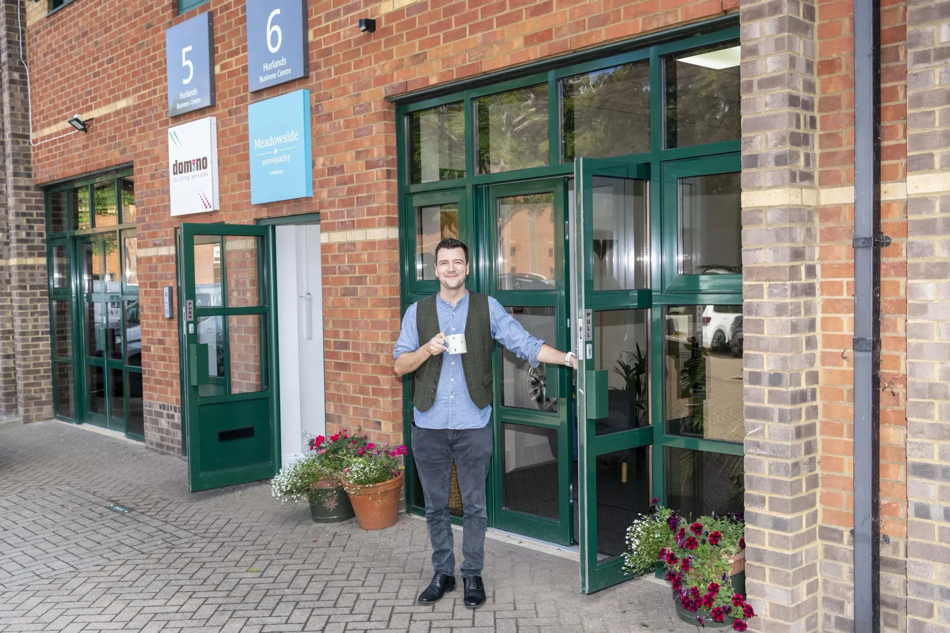 A picture of Josh, as he stands welcomingly, in front of Meadowside Osteopathy in Farnham.