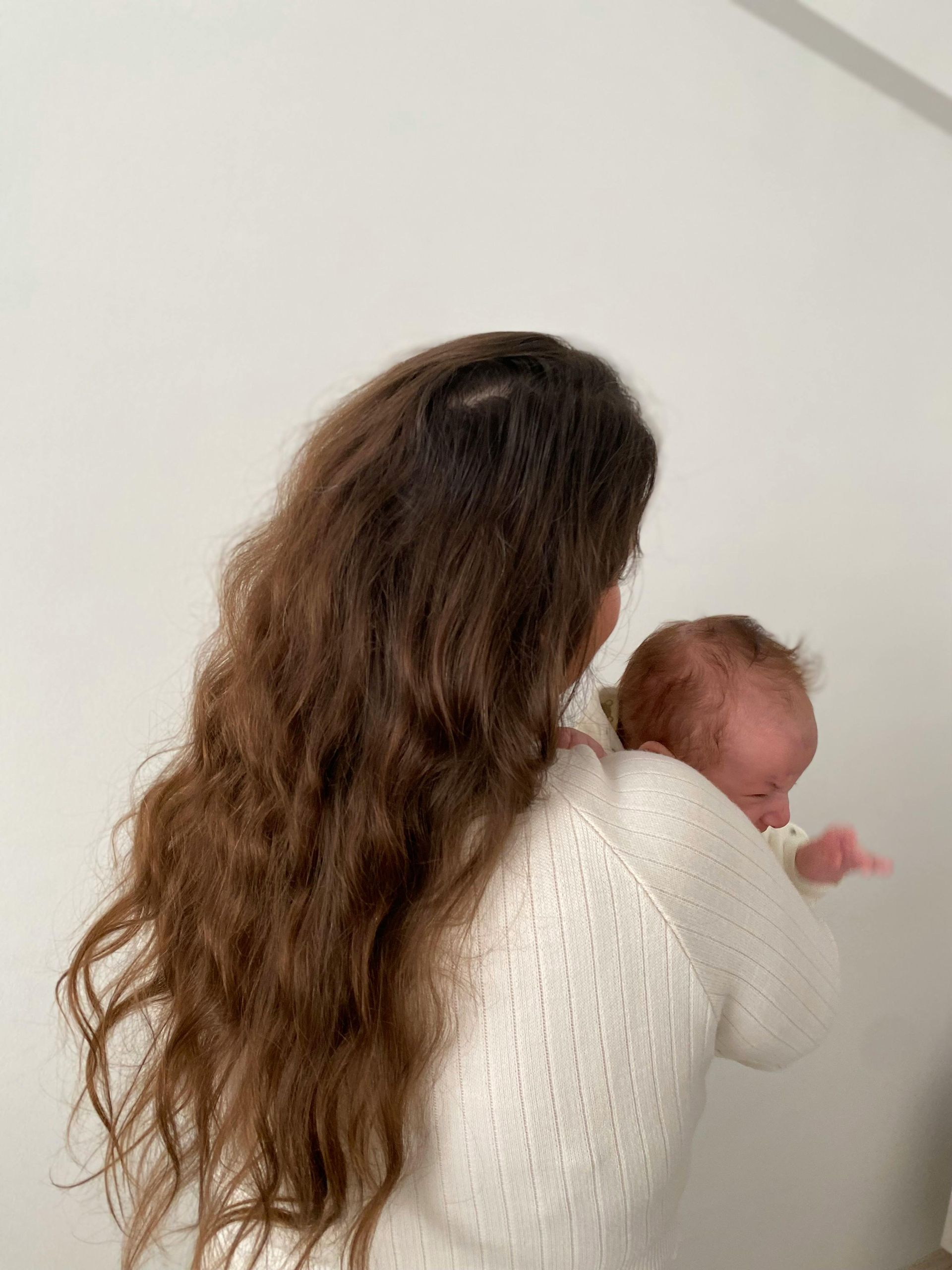 Mother sitting with newborn looking thoughtful – postpartum depression therapy Hamilton Ontario