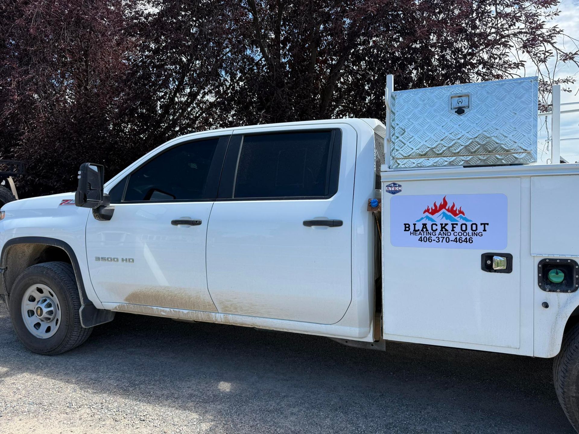 A white service truck with a metal utility box and 