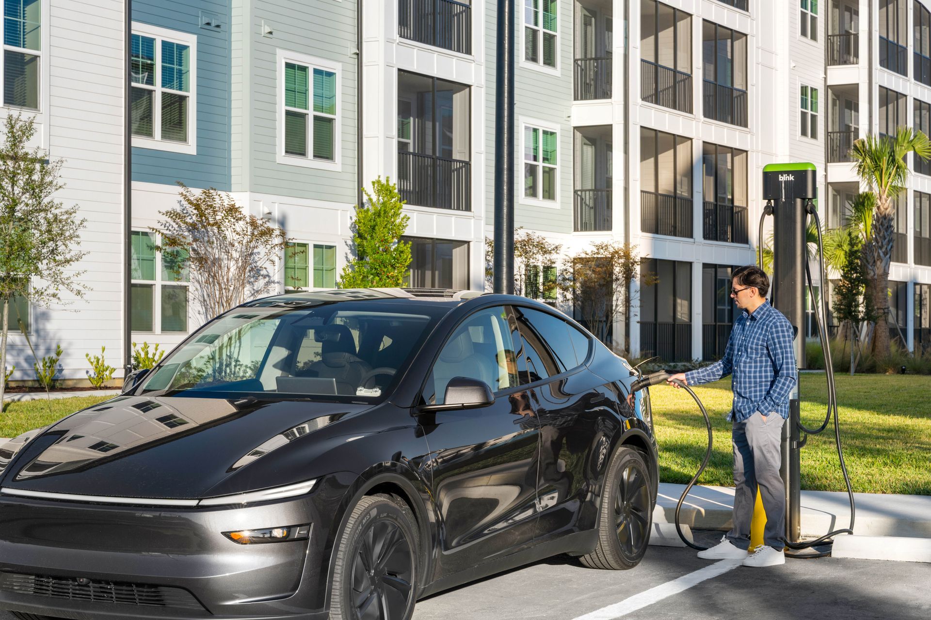 Man outside of building charging his car.