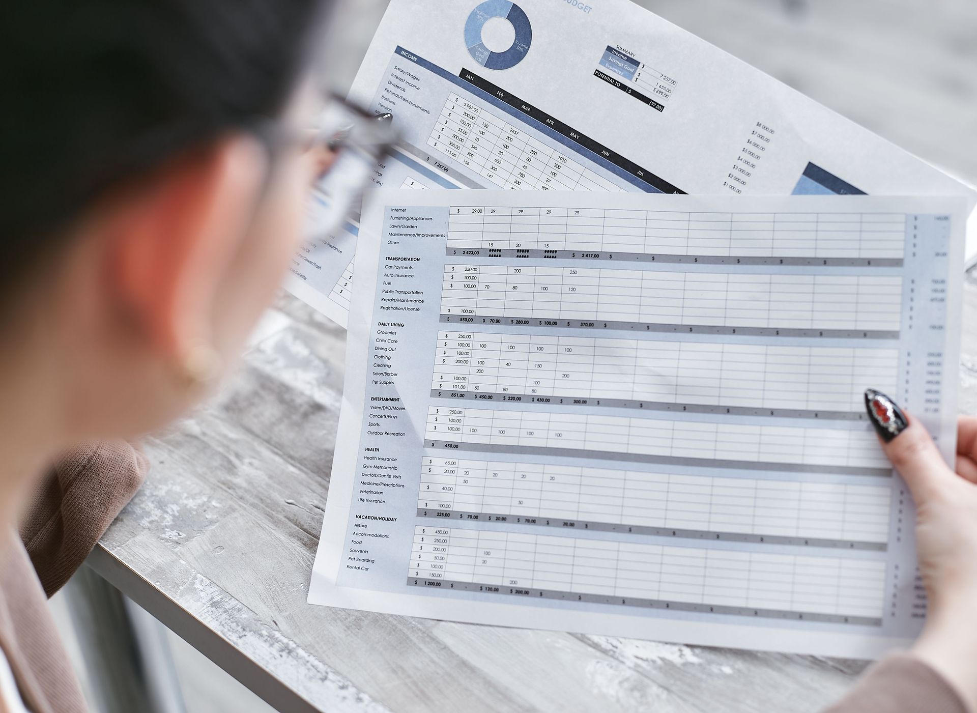 Person reviewing a financial form and pen on a desk with printed documents