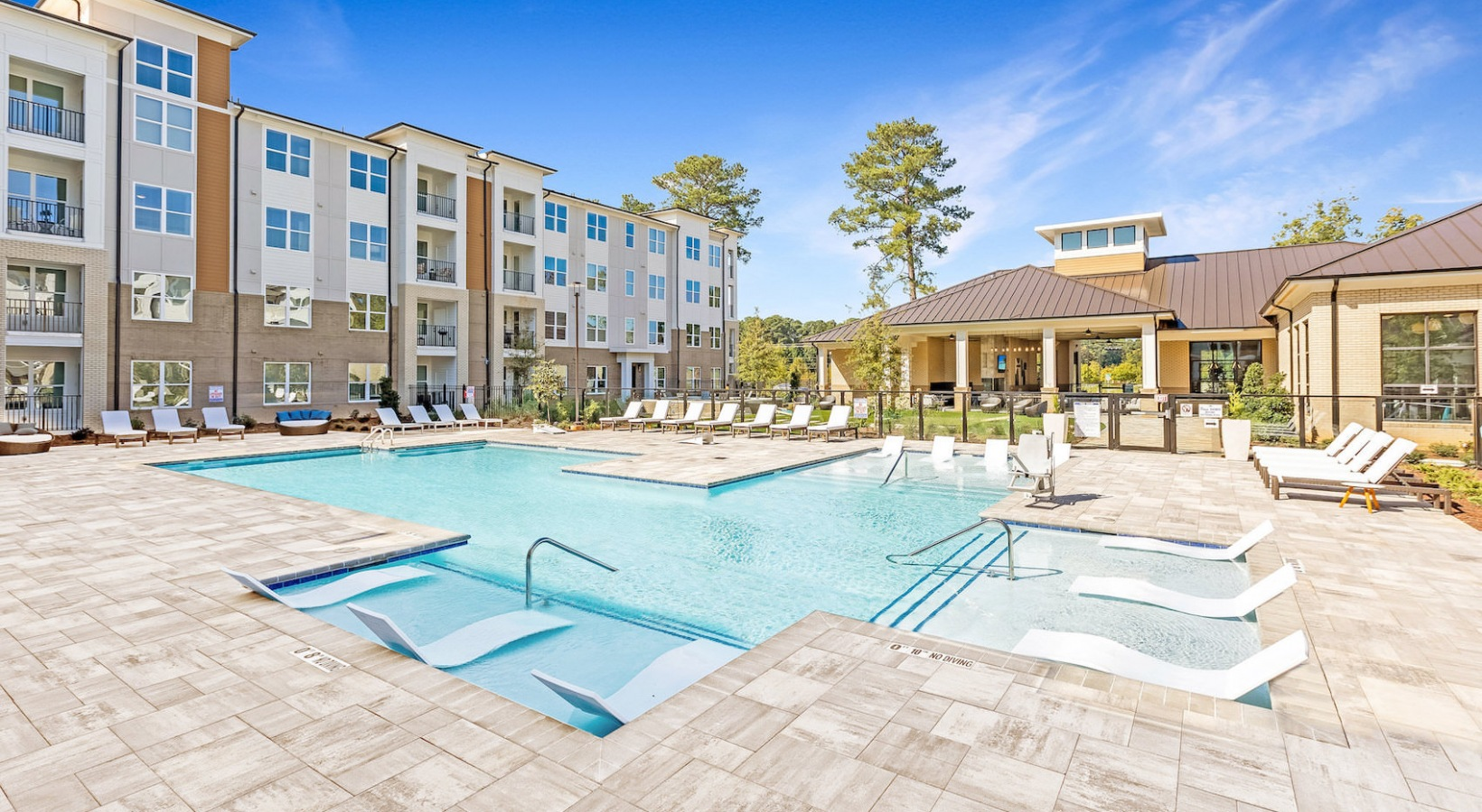 Apartment courtyard with a pool, lounge chairs, and a shaded pavilion on a sunny day
