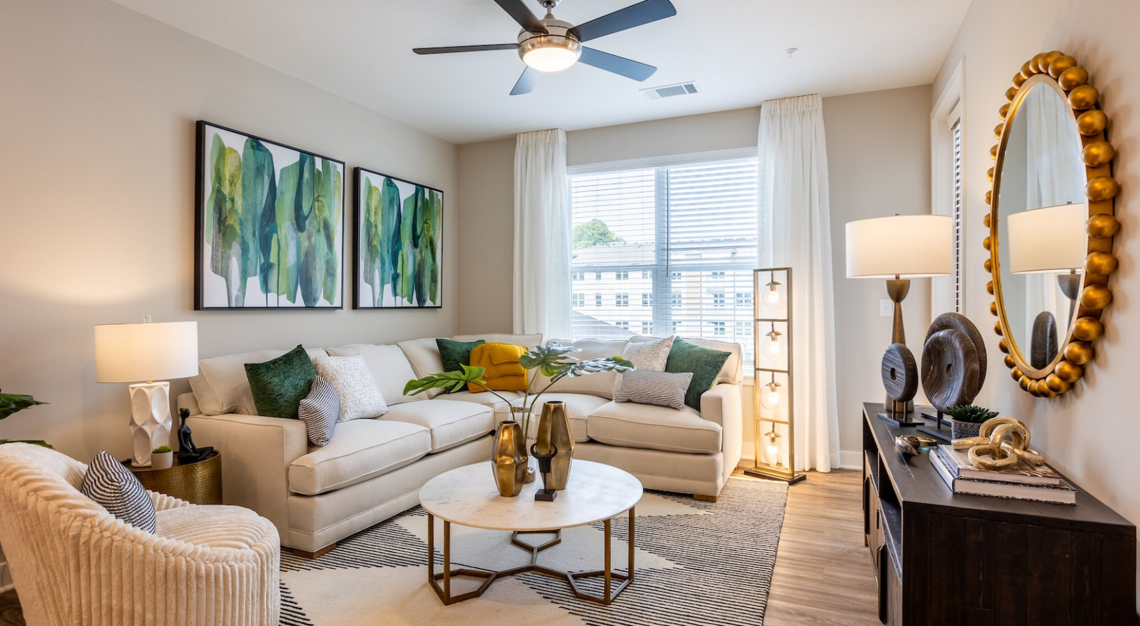 Bright living room with sectional sofa, abstract wall art, gold mirror, and window light