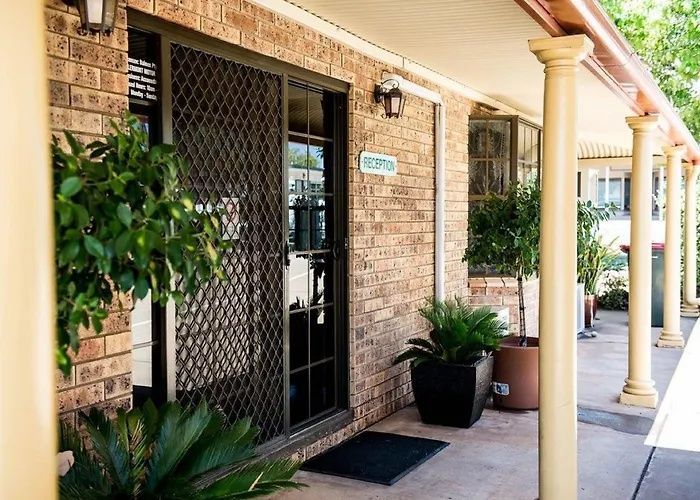 Brick apartment entryway with black security door, potted plants, and yellow columns