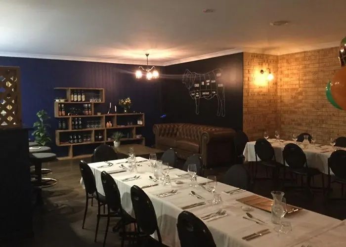 Empty restaurant dining room with set tables, dark walls, and warm wall sconces