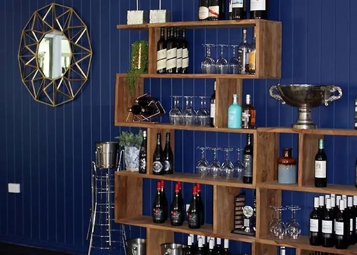 Wooden bar shelves with wine bottles, glasses, and decor against a dark blue wall
