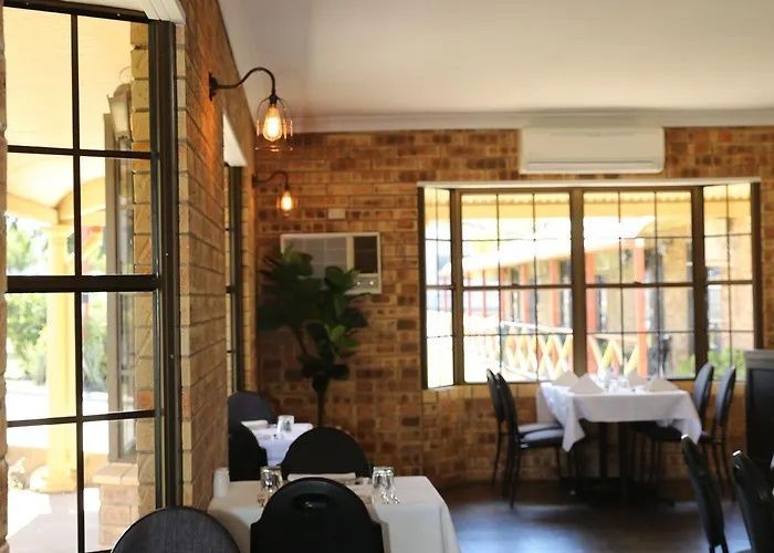Cozy restaurant dining area with brick walls, white-tablecloth tables, and large windows overlooking a balcony.