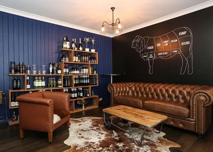 Stylish lounge with leather sofa, armchair, bar shelves, and a cow mural on a dark blue wall.