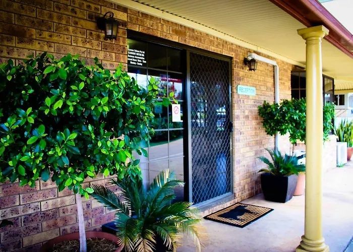 Brick storefront entrance with potted plants, a black security door, and a covered walkway