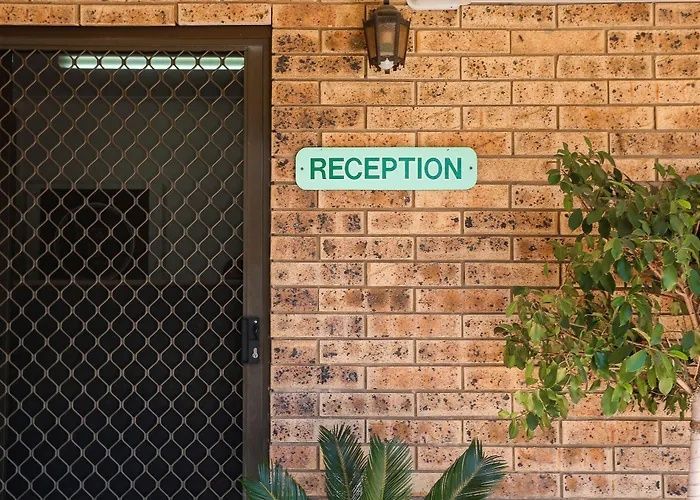 Brick wall with a turquoise “RECEPTION” sign beside a screened entrance and potted plants Brick wall with a turquoise “RECEPTION” sign beside a screened entrance and potted plants