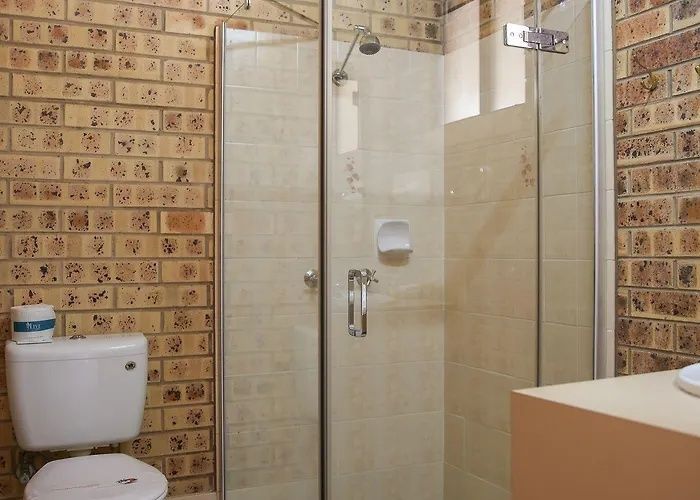 Small bathroom with shower, toilet, tiled walls, and beige vanity sink.