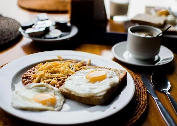 Breakfast plate with eggs, hash browns, toast, and a cup of coffee on a wooden table