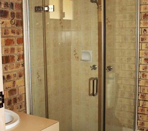 Bathroom with a glass shower enclosure beside a sink and brick-patterned walls