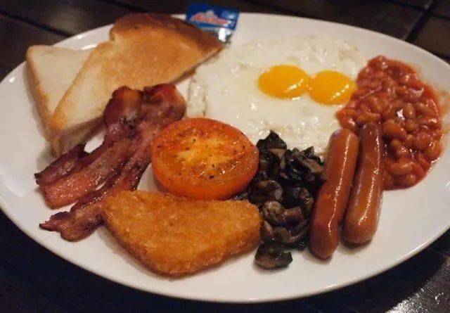 Breakfast plate with toast, bacon, eggs, beans, sausages, mushrooms, and hash browns