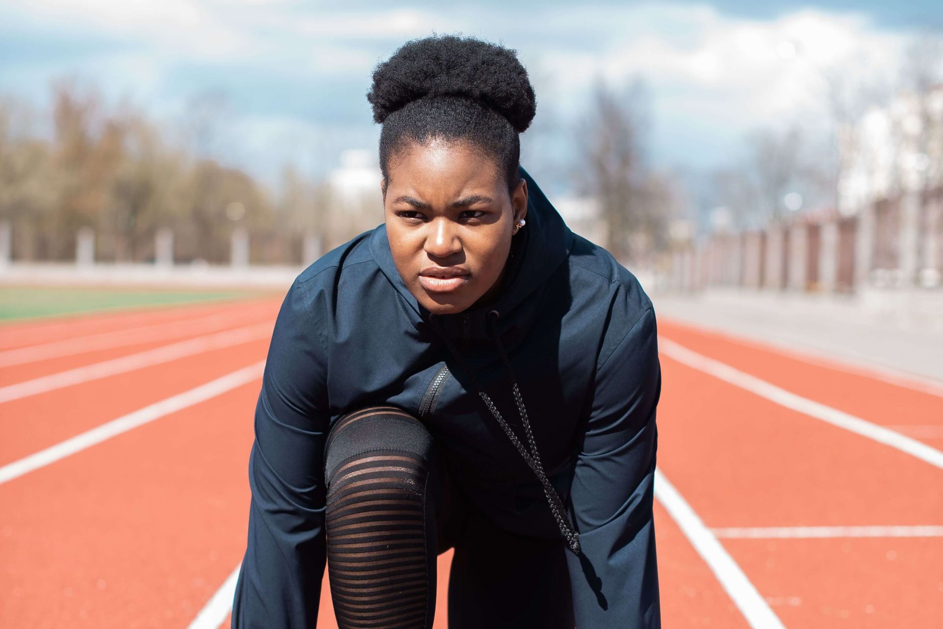 Woman standing on an outdoor track. Sports performance anxiety therapy in Omaha, NE, can help.