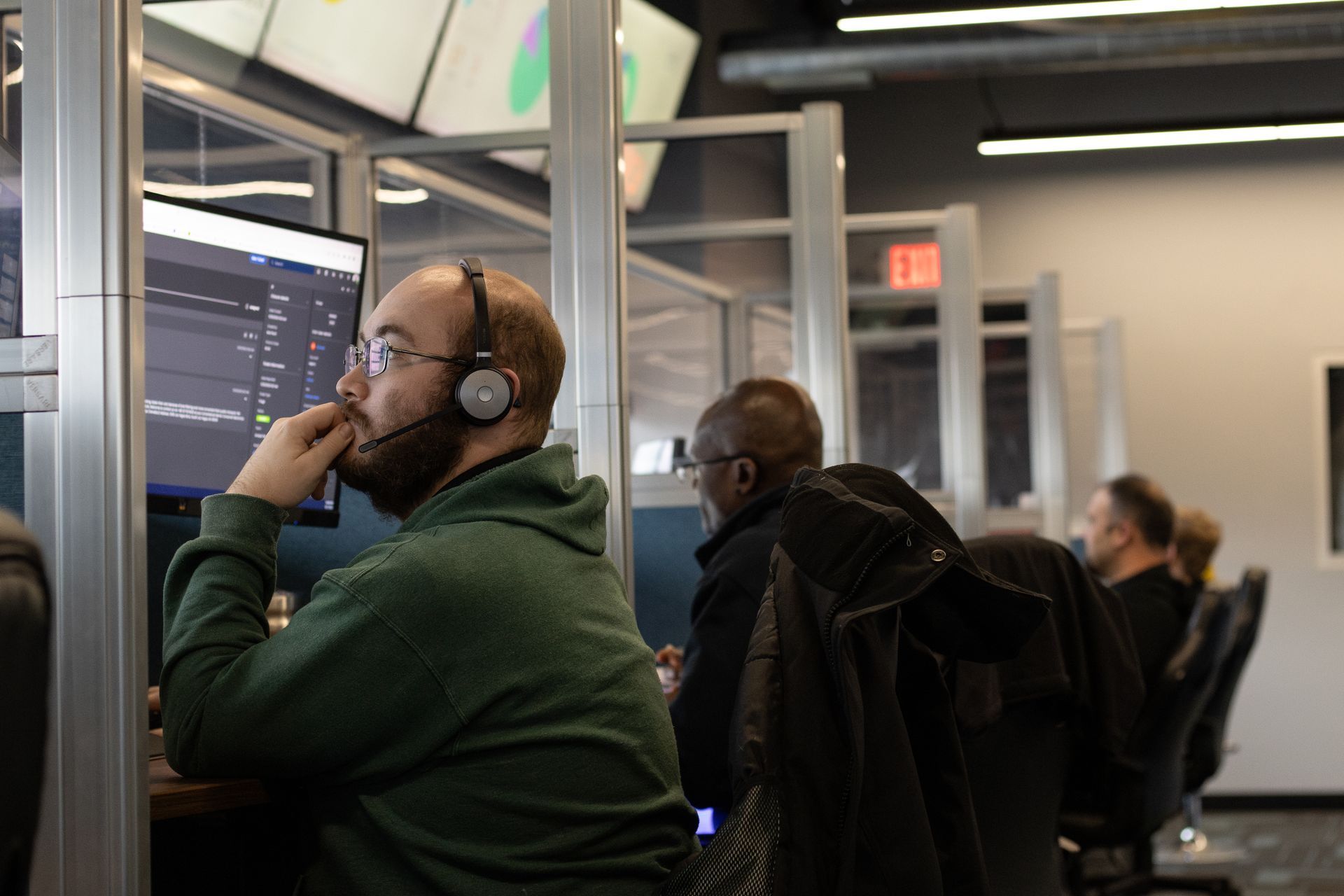 A man wearing headphones sits in front of a computer