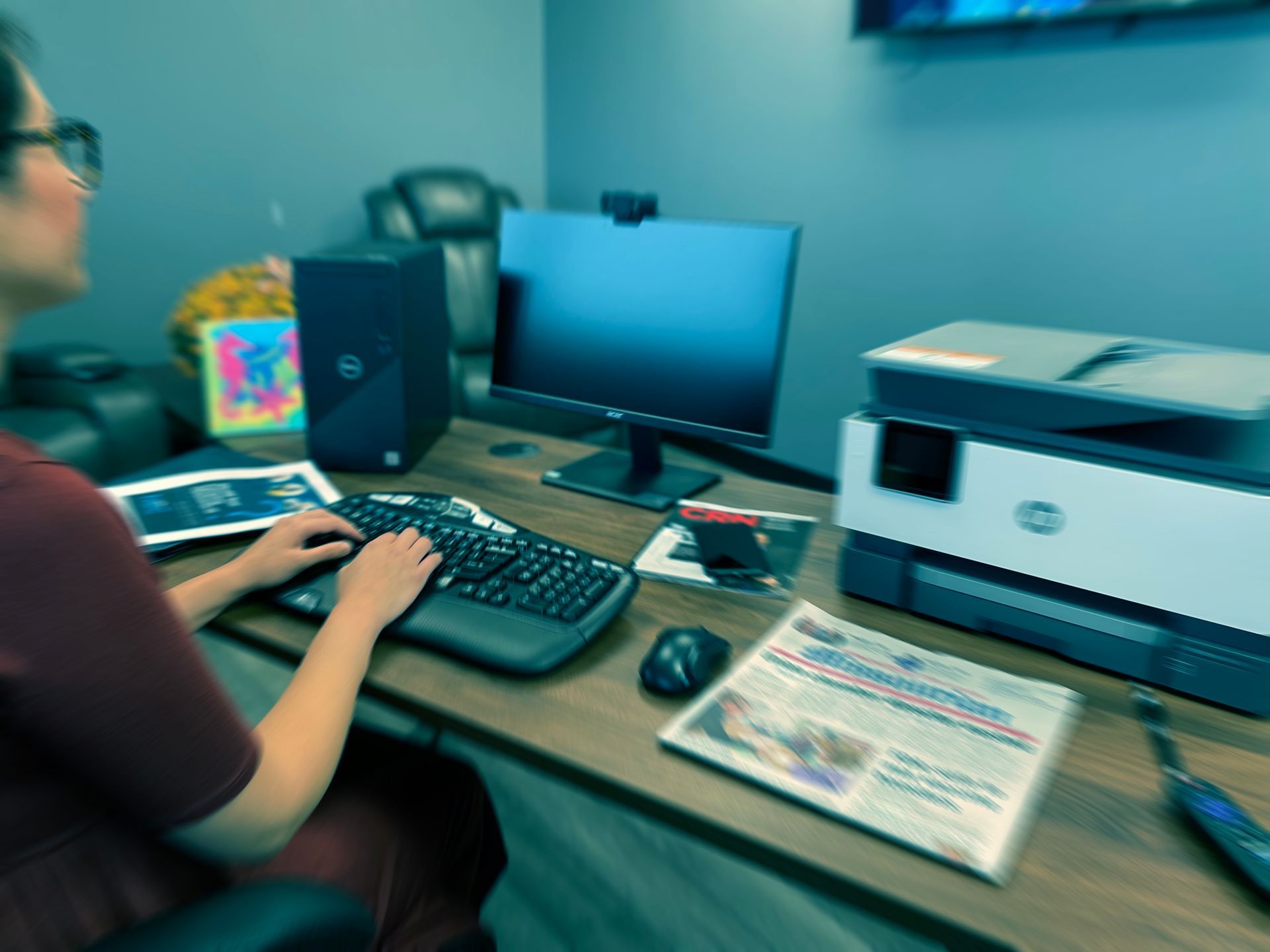 A woman is typing on a keyboard in front of an hp printer