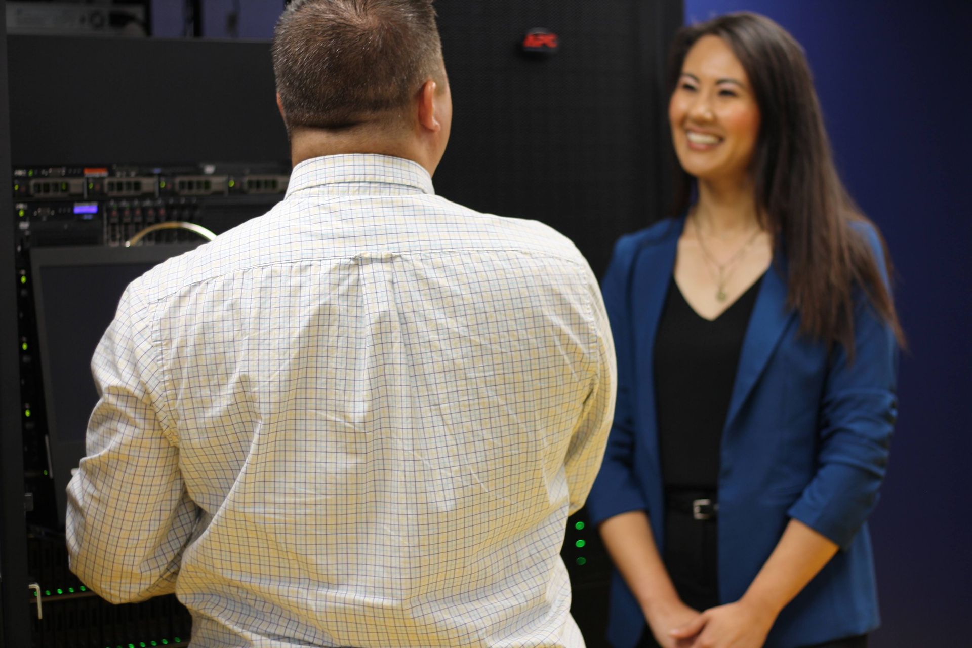 A woman smiles at a man near server racks.