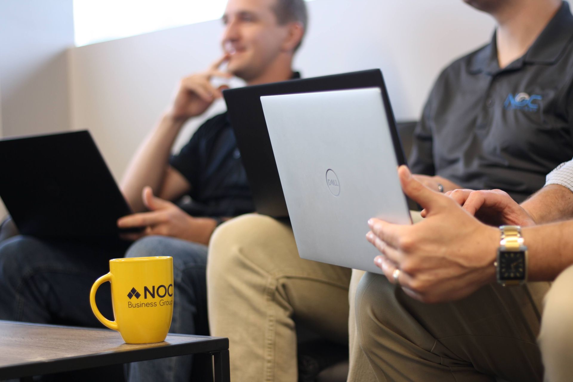 Three men in an office setting, using laptops need IT support