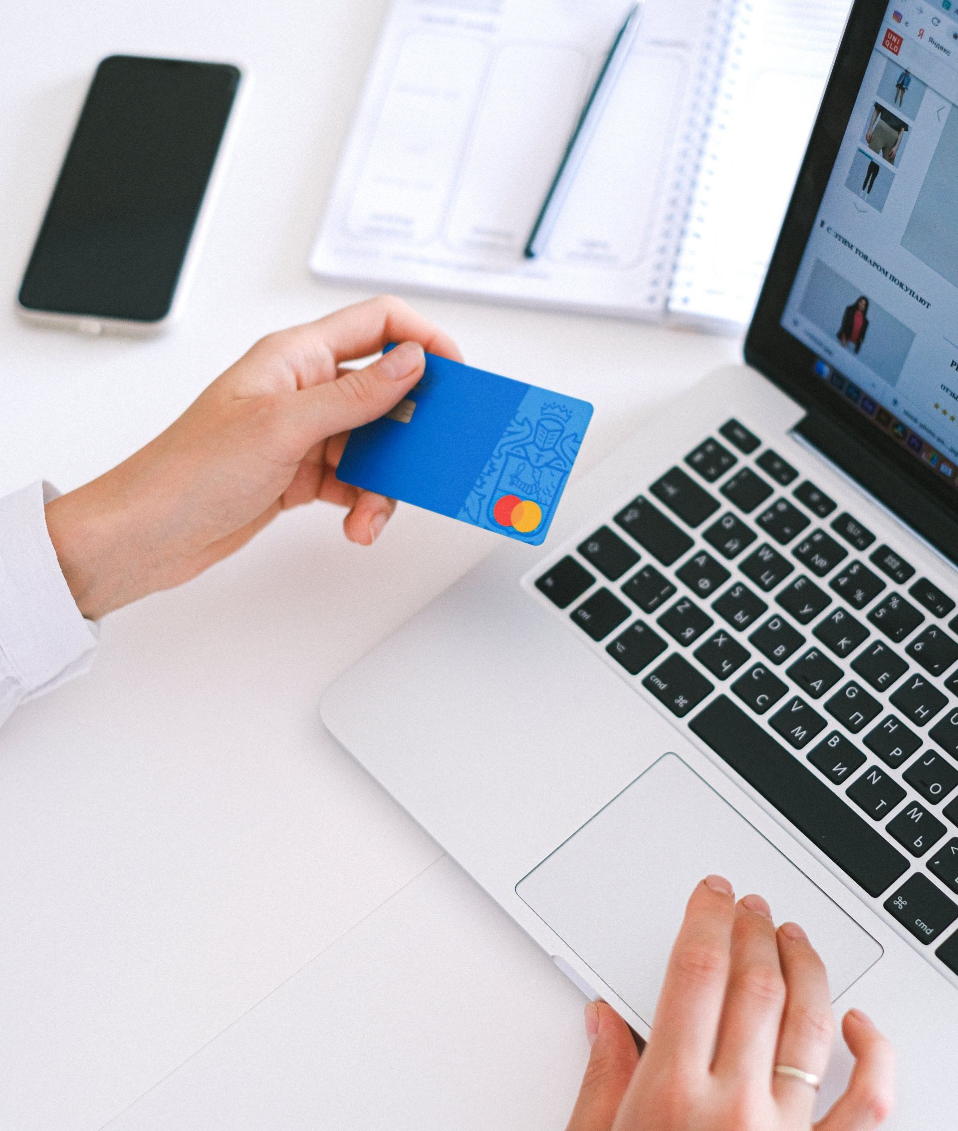 A person holding a credit card in front of a laptop