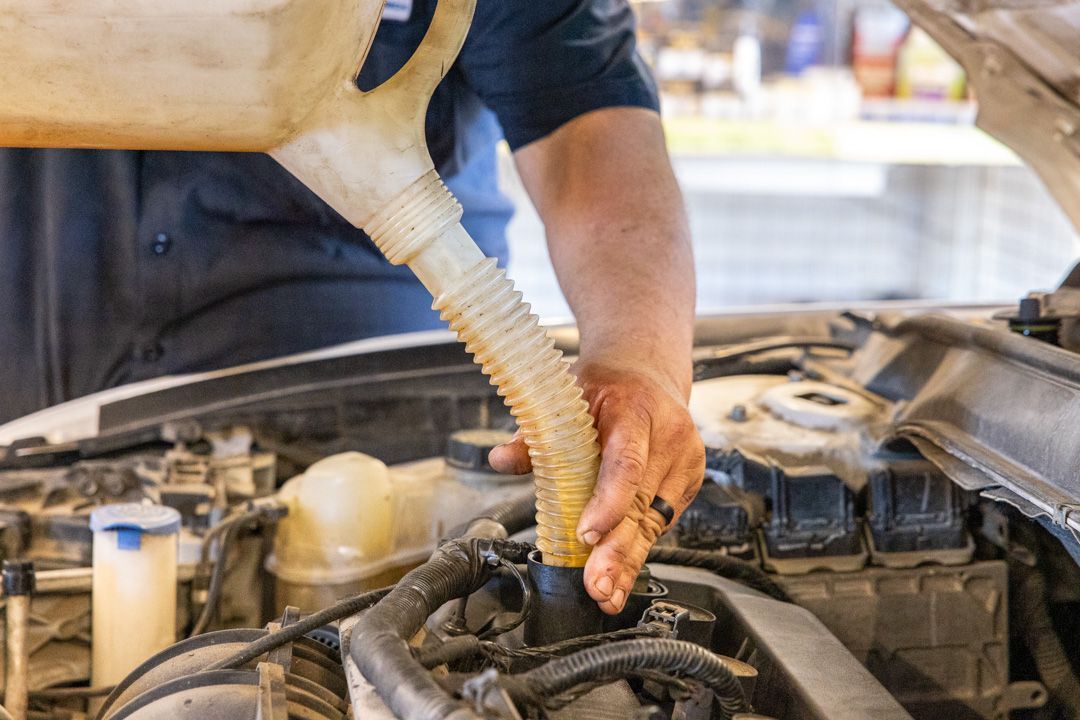 Person pouring oil into a car engine using a funnel.