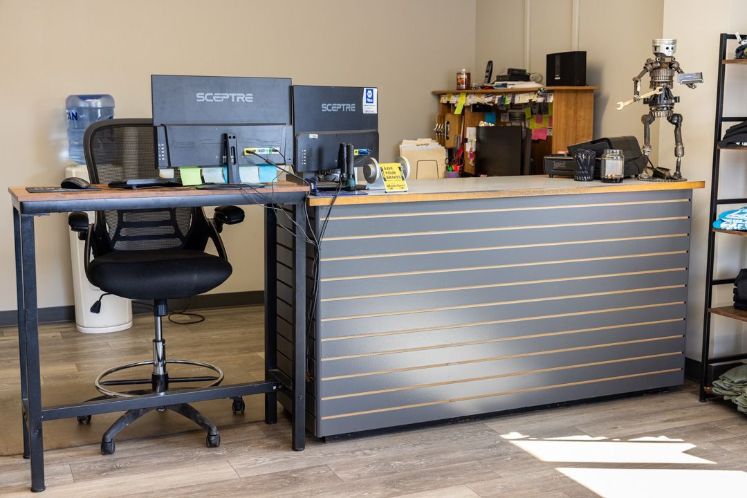 Desk with computer monitors, office chair, and gray slat-wall counter.