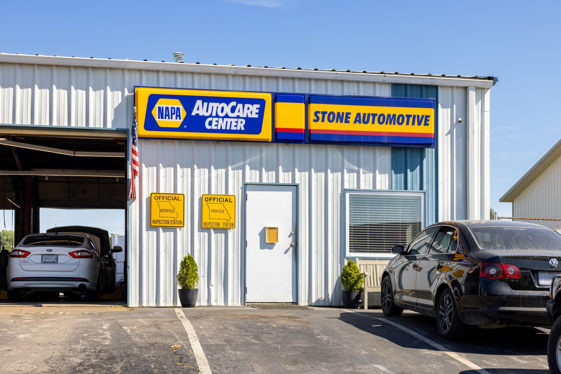 Stone Automotive building with the NAPA AutoCare Center sign; a car is in the open garage.