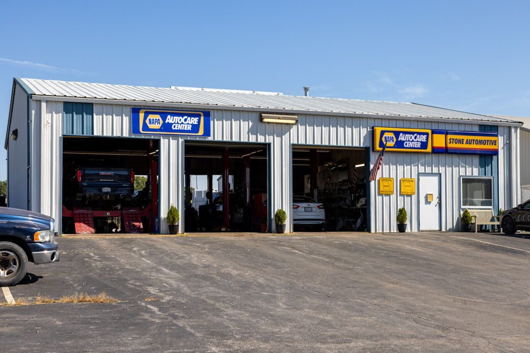Auto repair shop with three bays, NAPA AutoCare signage, blue and white exterior, blue pickup truck.