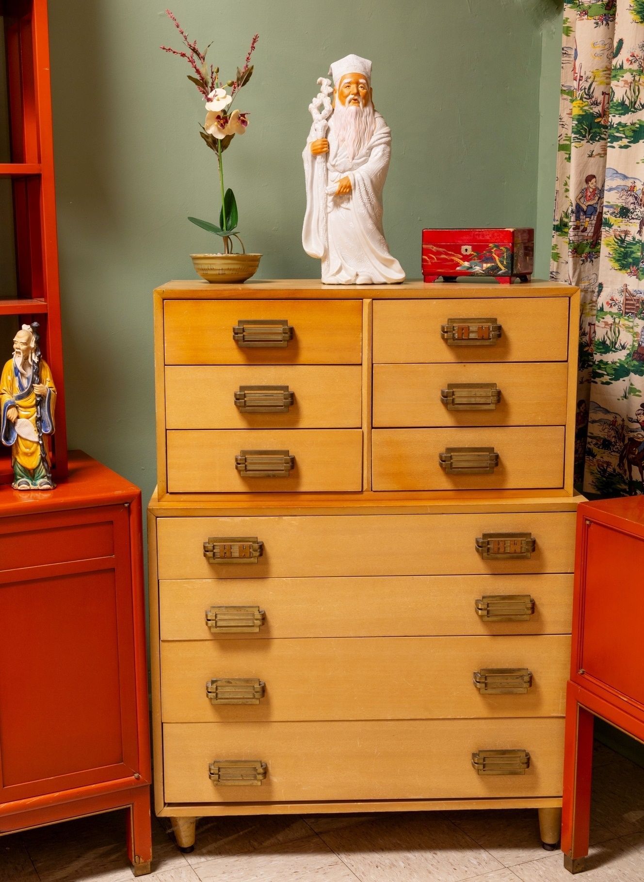 A wooden dresser with a statue of a man on top of it.