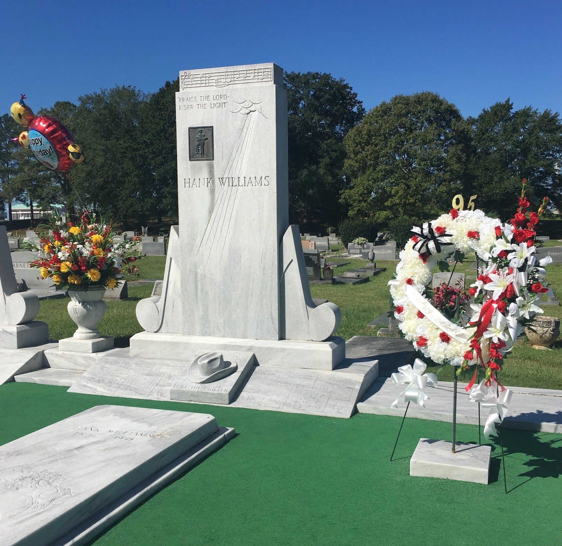 A memorial in a cemetery with flowers and a wreath