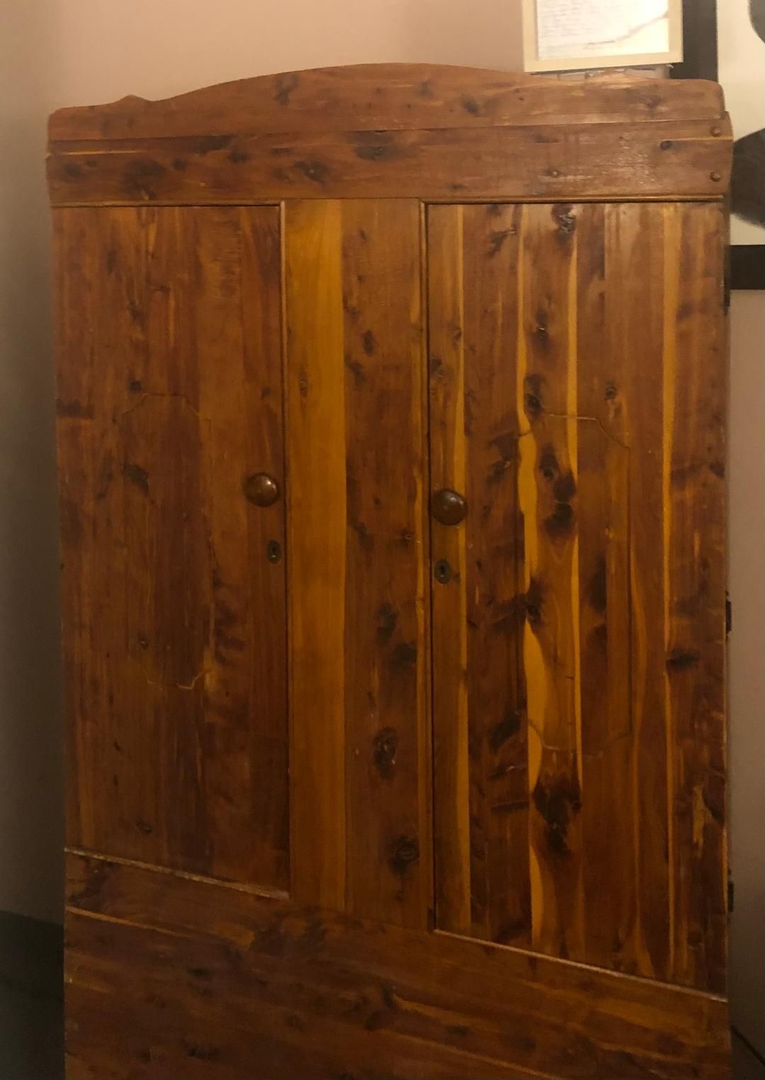 A wooden cabinet is sitting in a room next to a wall.