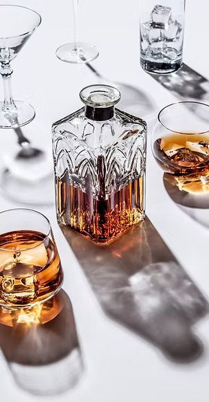 A bottle of whiskey and three glasses of whiskey on a table.