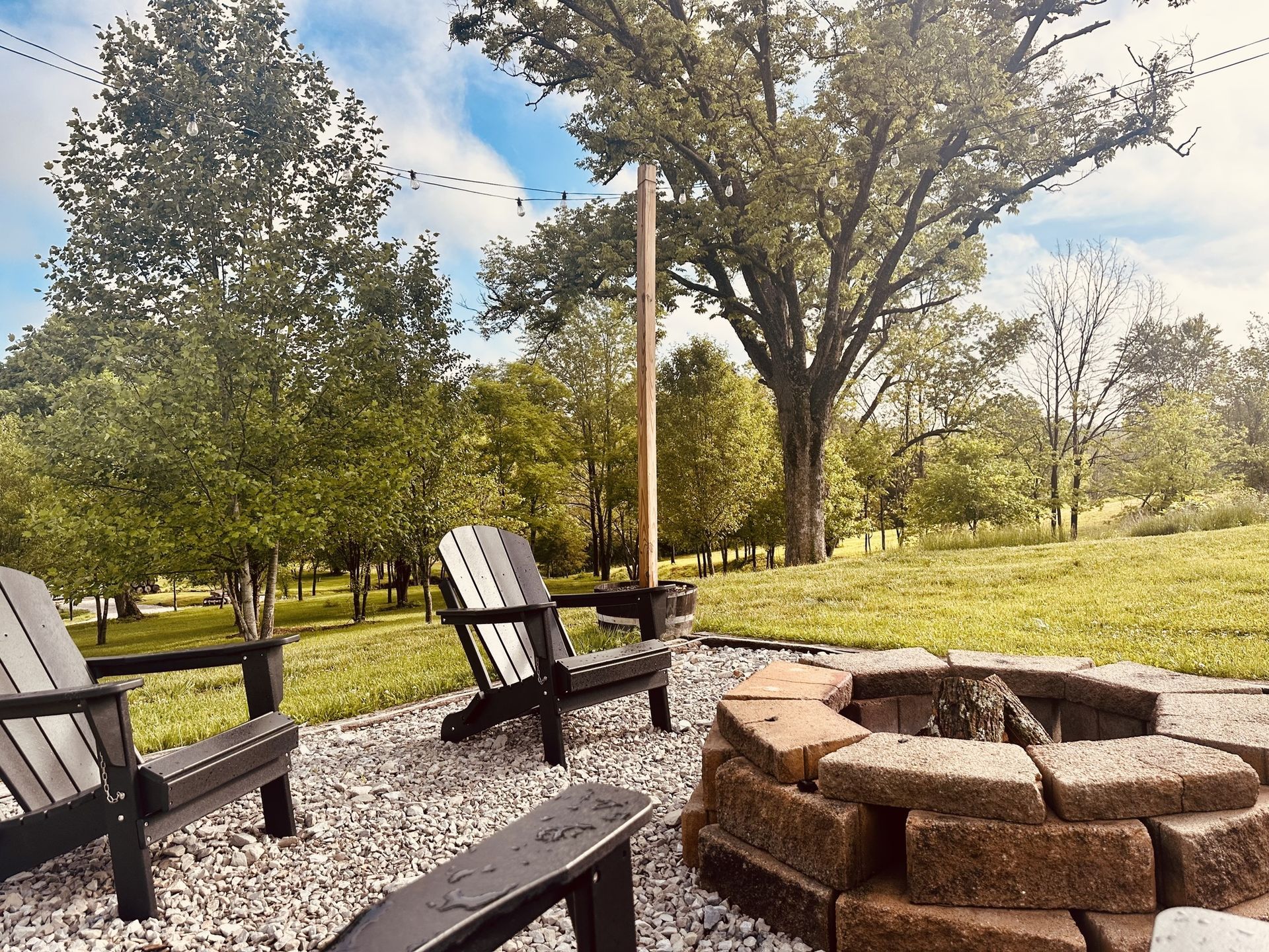 A fire pit surrounded by chairs in a yard with trees in the background.